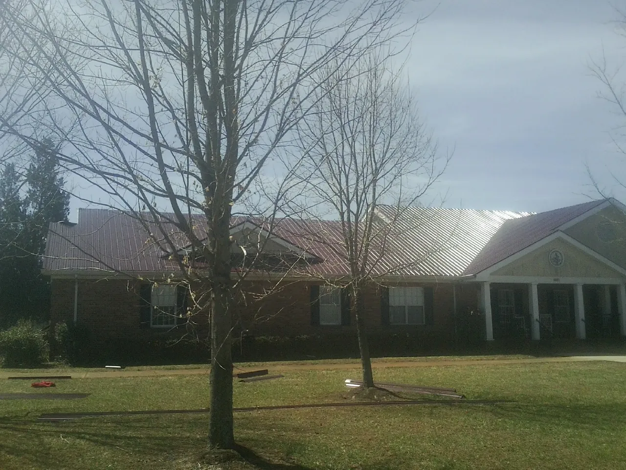 Red metal roof on a brick building seen from the front lawn in Cedar Creek